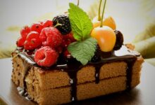 A delectable cake adorned with berries and chocolate syrup ralated to effect of delicious desserts