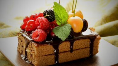 A delectable cake adorned with berries and chocolate syrup ralated to effect of delicious desserts