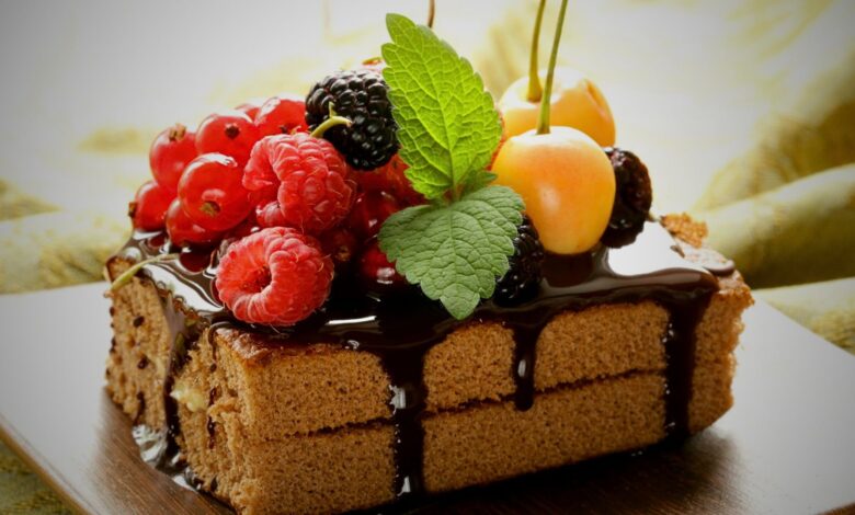 A delectable cake adorned with berries and chocolate syrup ralated to effect of delicious desserts