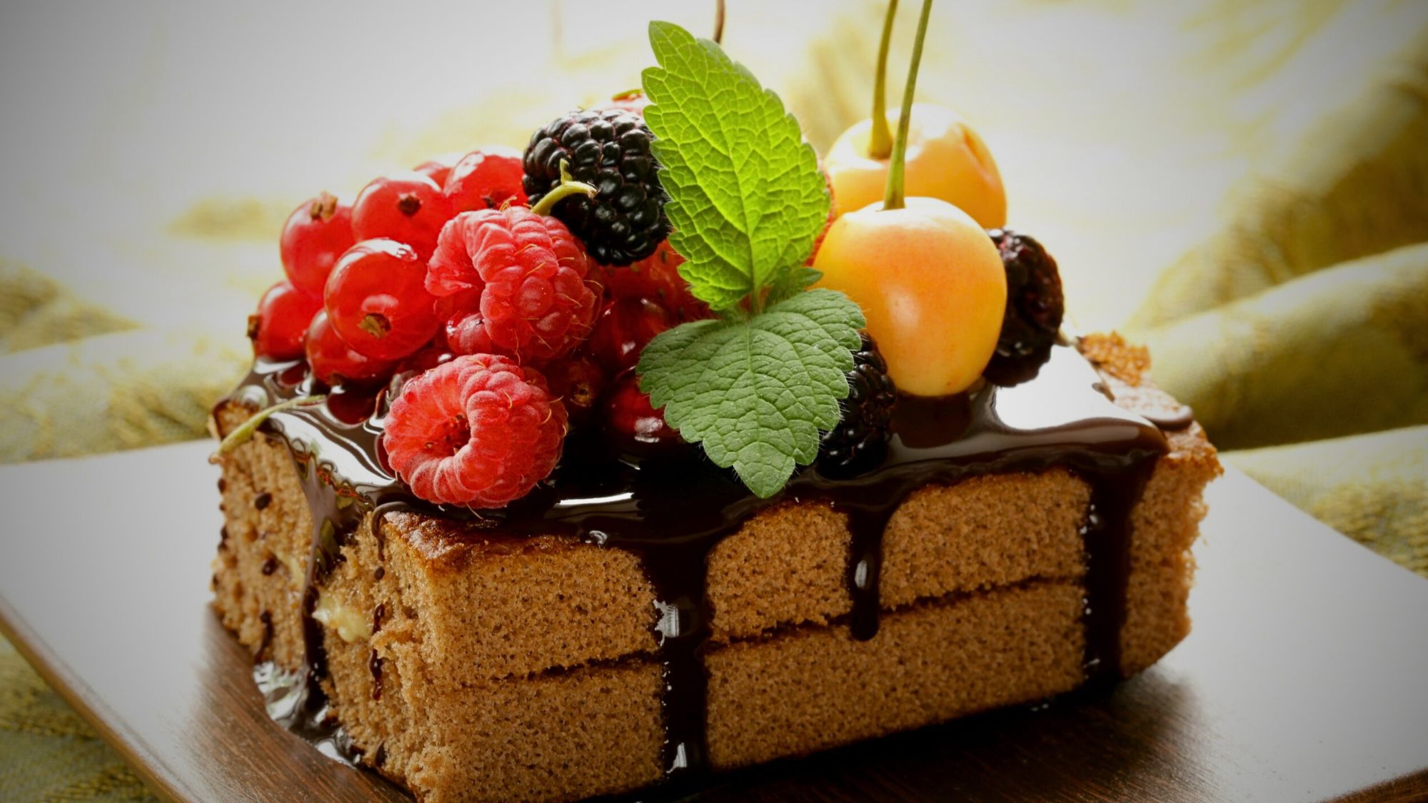 A delectable cake adorned with berries and chocolate syrup ralated to effect of delicious desserts